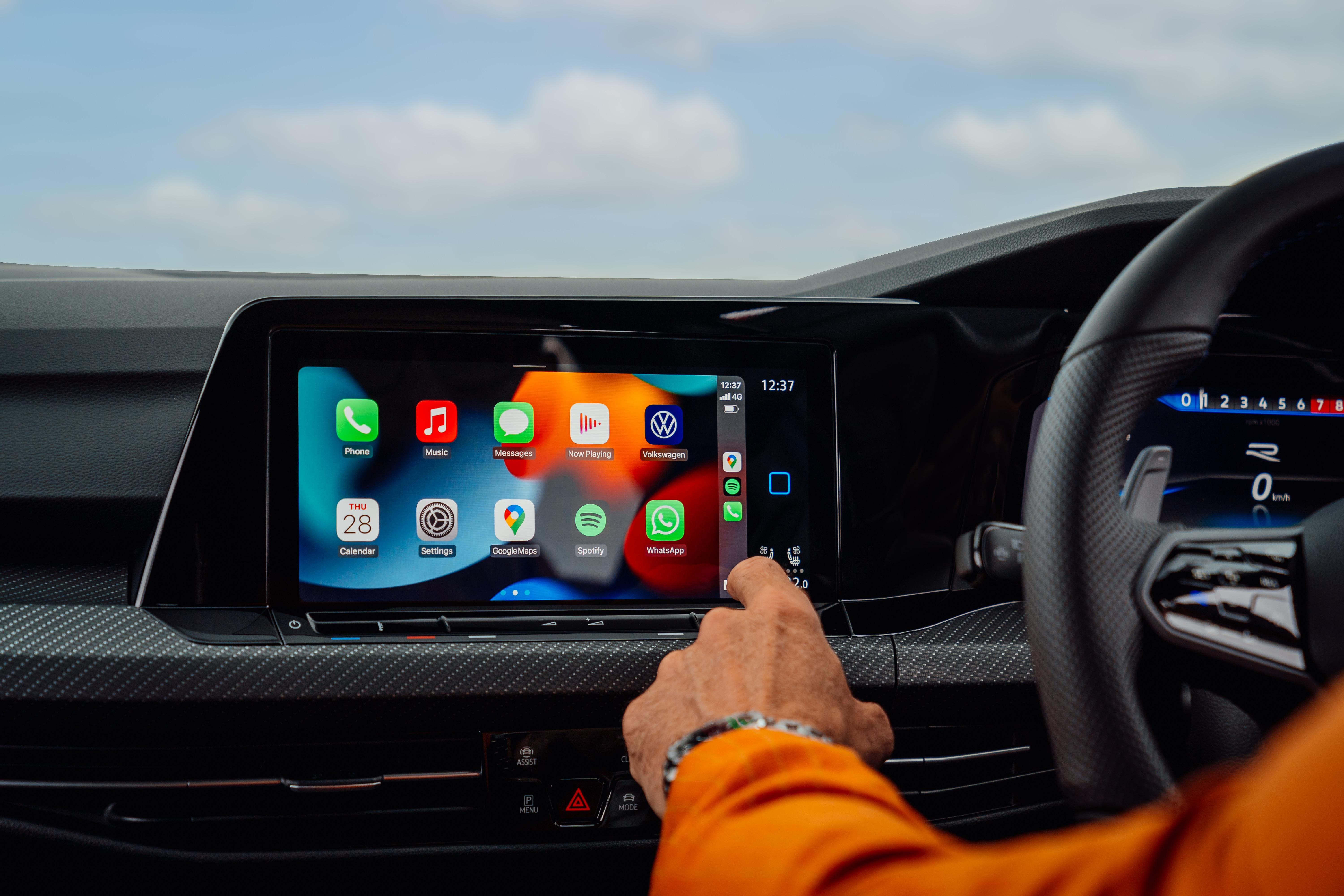 A driver taps through apps on a touchscreen — the kind of interface Allianz respondents say they'd rather replace with physical controls.