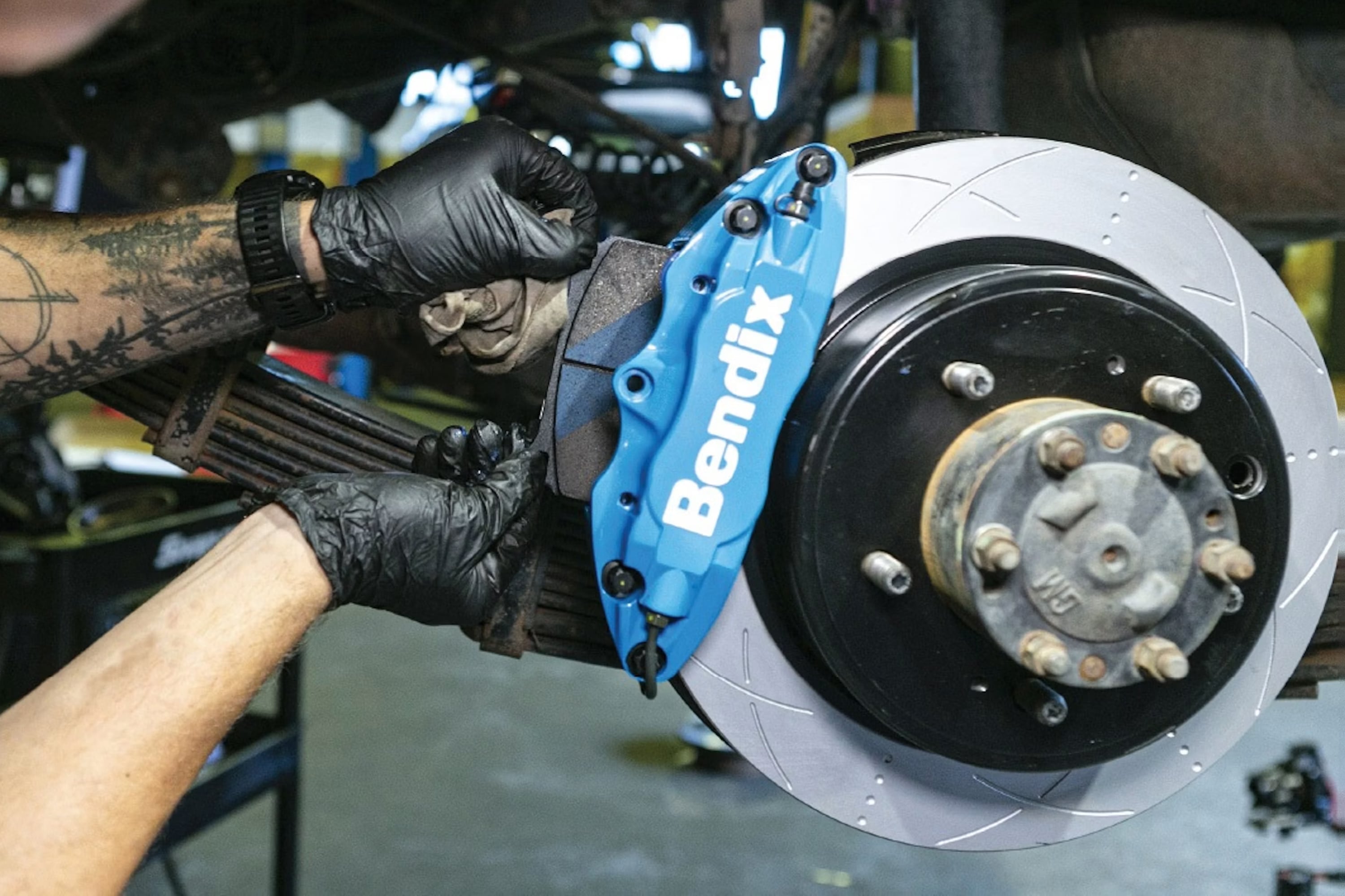 A technician fits a Bendix brake caliper and rotor, the kind of product at the centre of FMP Group's Australian operations.