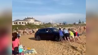 Porsche pandemonium on busy beach as luxury SUV gets bogged