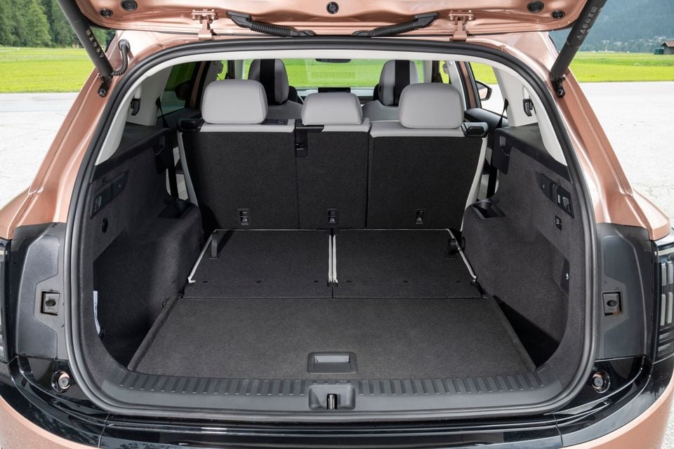 The empty boot of a Skoda Elroq SUV with the tailgate open, showing a spacious carpeted cargo area and rear seat headrests visible beyond