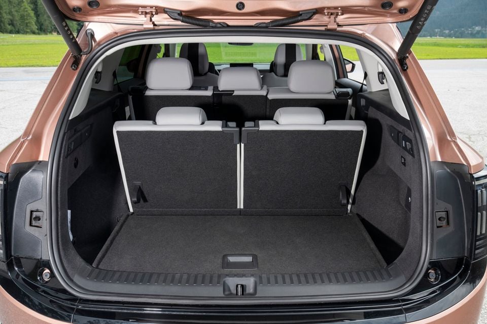 Open boot of a bronze Skoda Enyaq SUV showing a spacious cargo area with rear seats visible