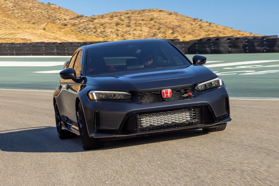 A dark grey 2027 Honda Civic Type R hatchback being driven on a racetrack, seen from the front quarter view.