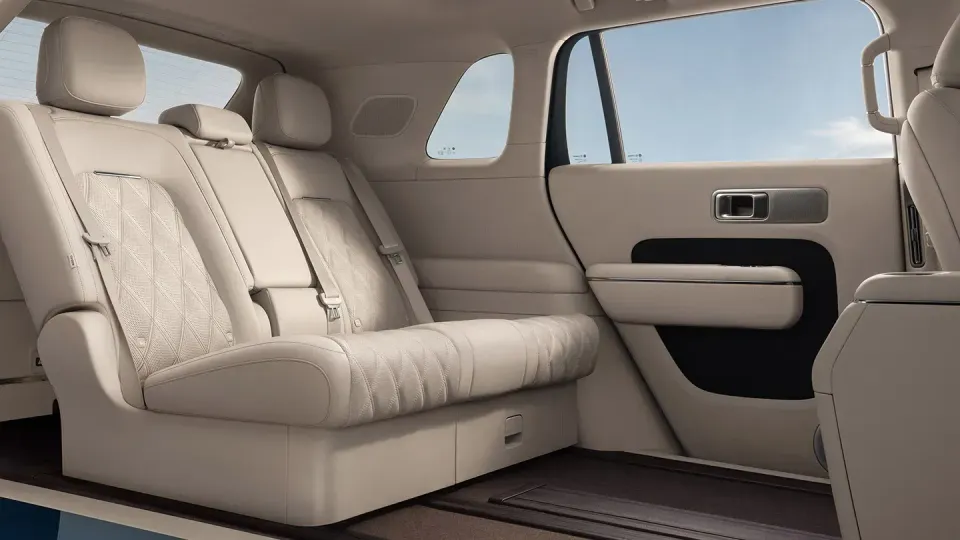 Cream leather rear seats of an SUV interior, viewed through an open door, showing quilted upholstery and a beige door panel