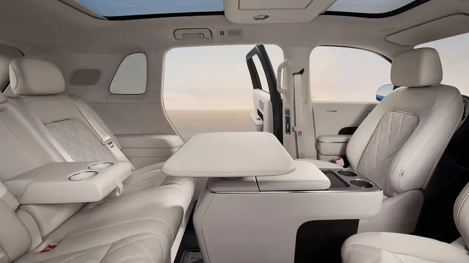 Luxurious cream leather interior of the Xiaomi SkyNomad N90 showing second-row captain's chairs with a fold-out centre table, cup holders, and a panoramic sunroof overhead