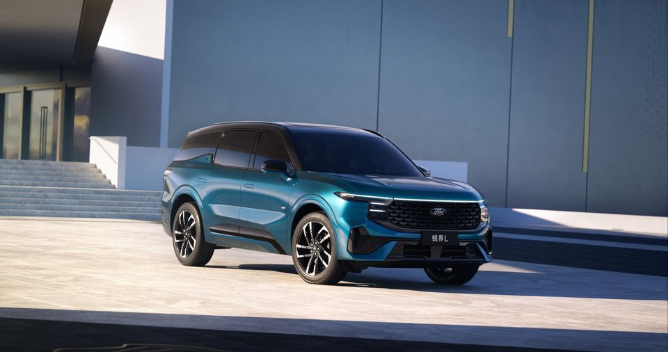 A teal Ford Edge L SUV seen from the front-side angle, parked in a modern architectural setting