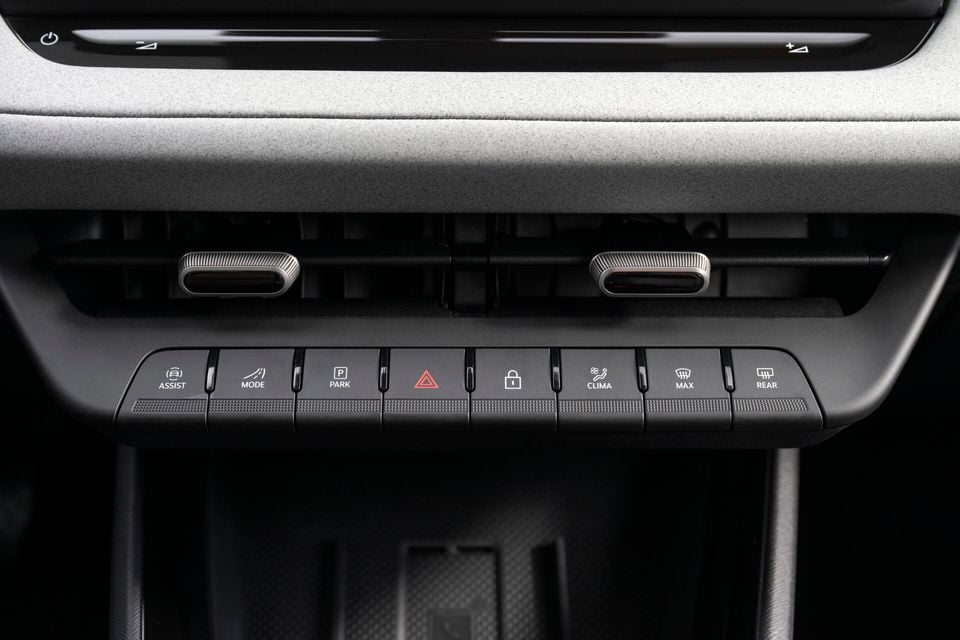Close-up of the centre console control panel in a Skoda Epiq, showing physical shortcut buttons for Assist, Mode, Park, hazard lights, lock, Clima, Max, and Rear, along with twin air vents above.