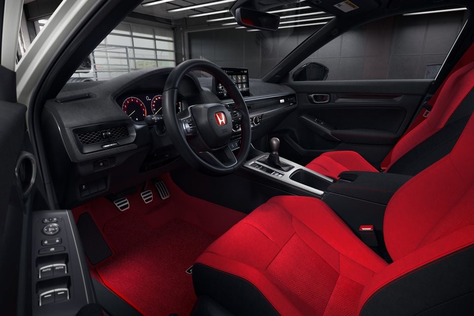 The interior of a 2027 Honda Civic Type R shows red and black sports seats, a manual gearshift, and a flat-bottom steering wheel.