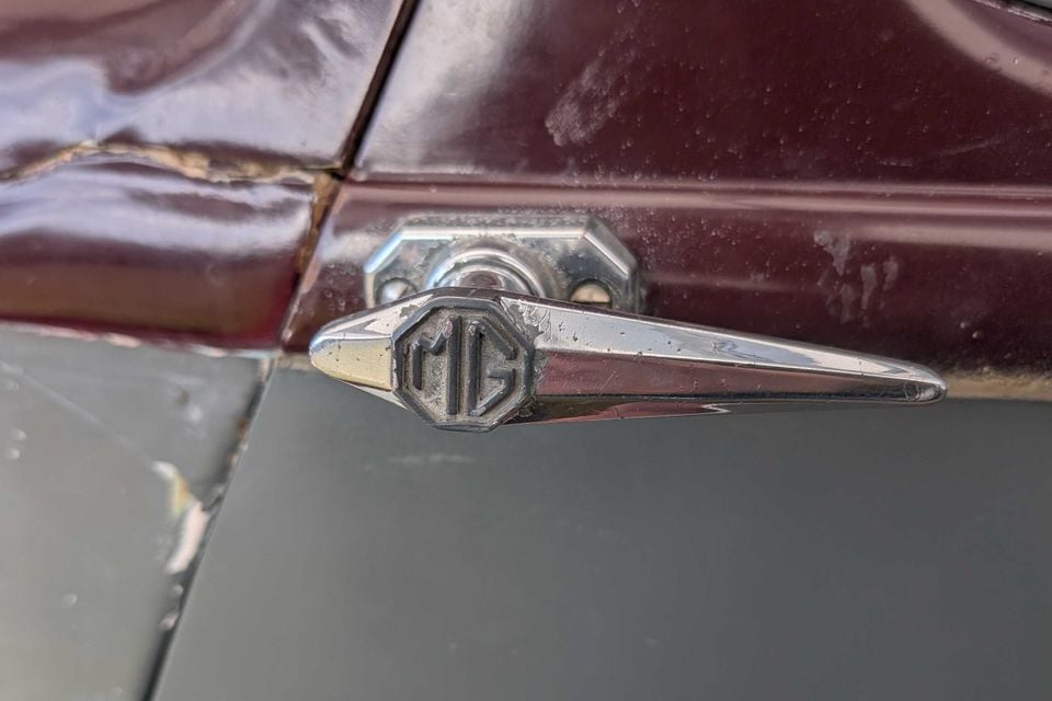 Close-up of the chrome MG-badged door handle on a maroon and grey 1936 MG SA saloon, showing worn paint and patina