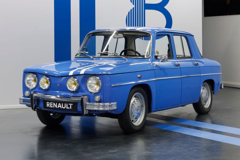 Um clássico sedã Renault 8 Gordini 1970 azul exibido em ambientes fechados, visto do ângulo frontal