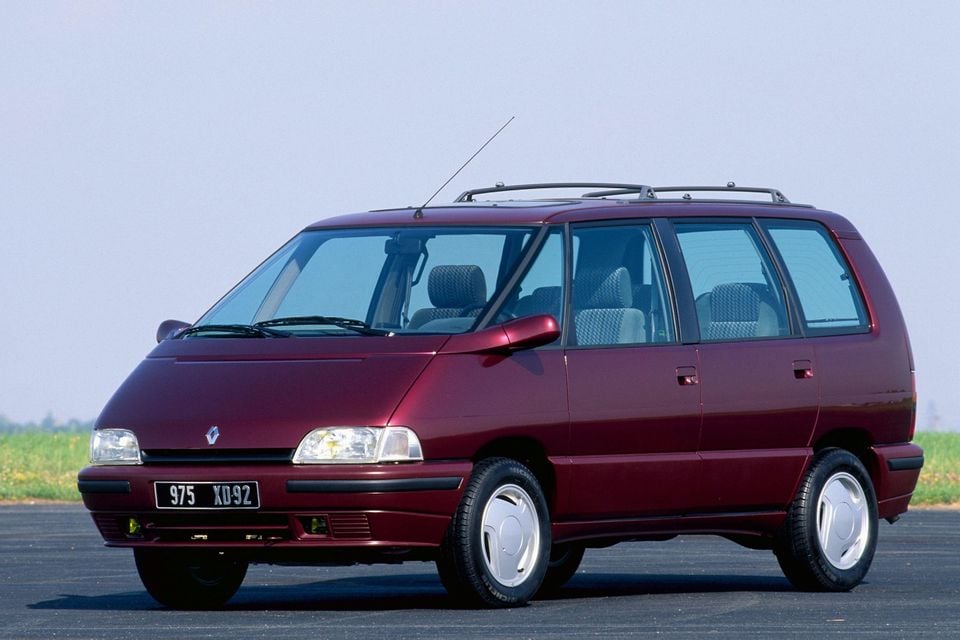 Uma minivan Renault Espace II marrom 1991 estacionada na calçada, vista do ângulo frontal.