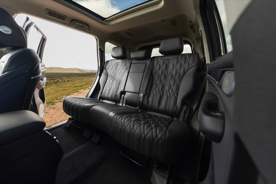 The black leather rear seats and sunroof of a 2026 GWM Tank 500 are visible through an open door, with a rural landscape outside.