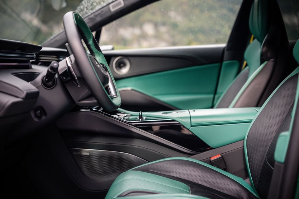 Green and black leather front seats, steering wheel and centre console inside the 2027 Lotus Eletre X, seen through the open passenger door