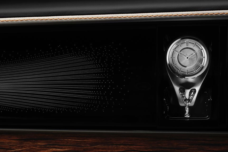 Dashboard of the 2027 Rolls-Royce Spectre with an illuminated starlight fascia, analogue clock and Spirit of Ecstasy figurine above wood veneer trim
