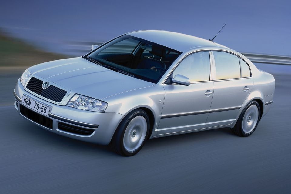 A silver Skoda Superb sedan seen from the front-side angle while driving on a road
