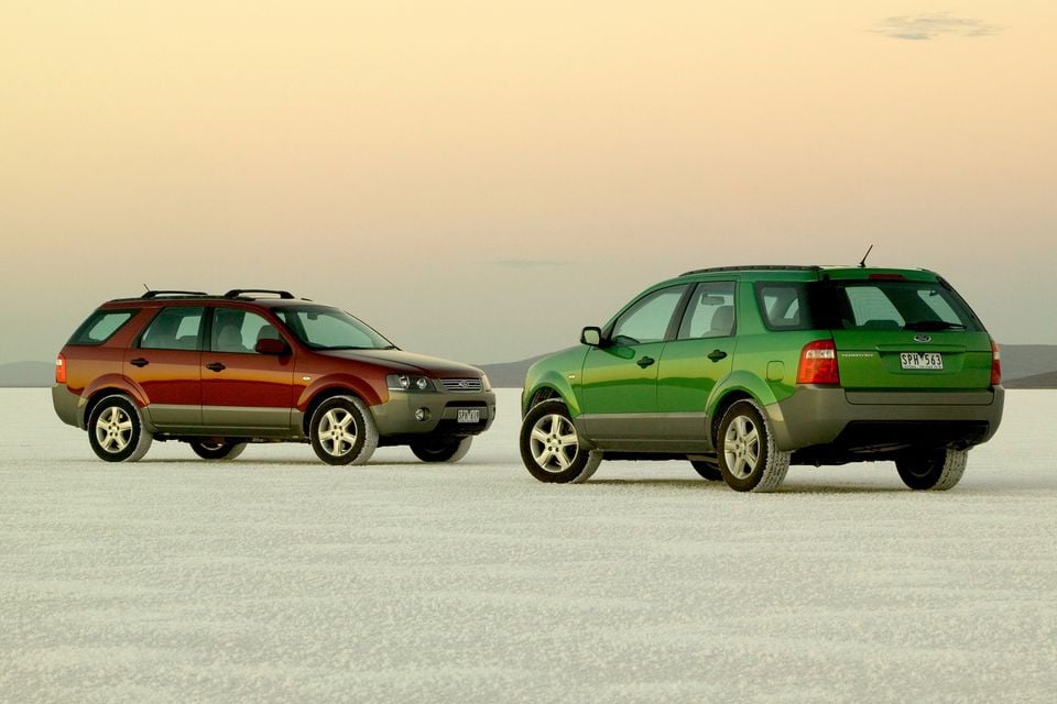 Two 2004 Ford Territory SUVs, one red and one green, parked on a salt flat at dusk, facing opposite directions