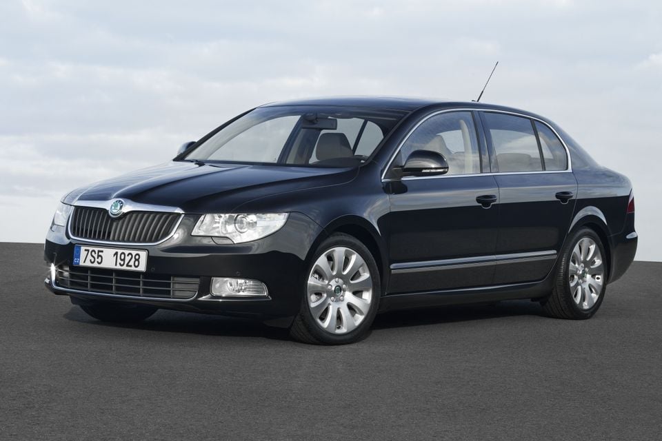 A dark blue 2009 Skoda Superb sedan seen from the front-left side, parked on an open surface under an overcast sky.