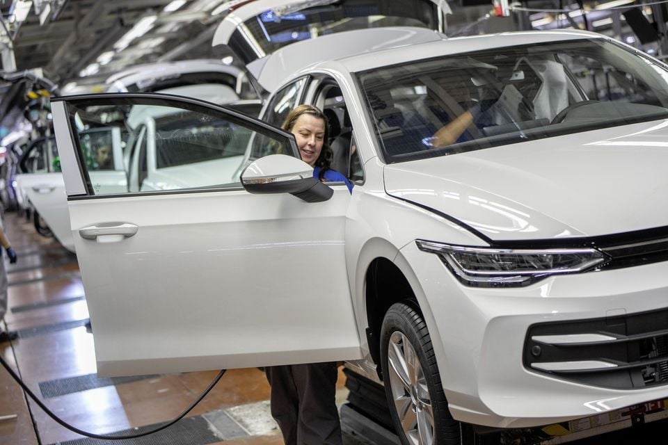 A factory worker inspects the door of a white Volkswagen Golf on the production line at the Wolfsburg manufacturing plant.