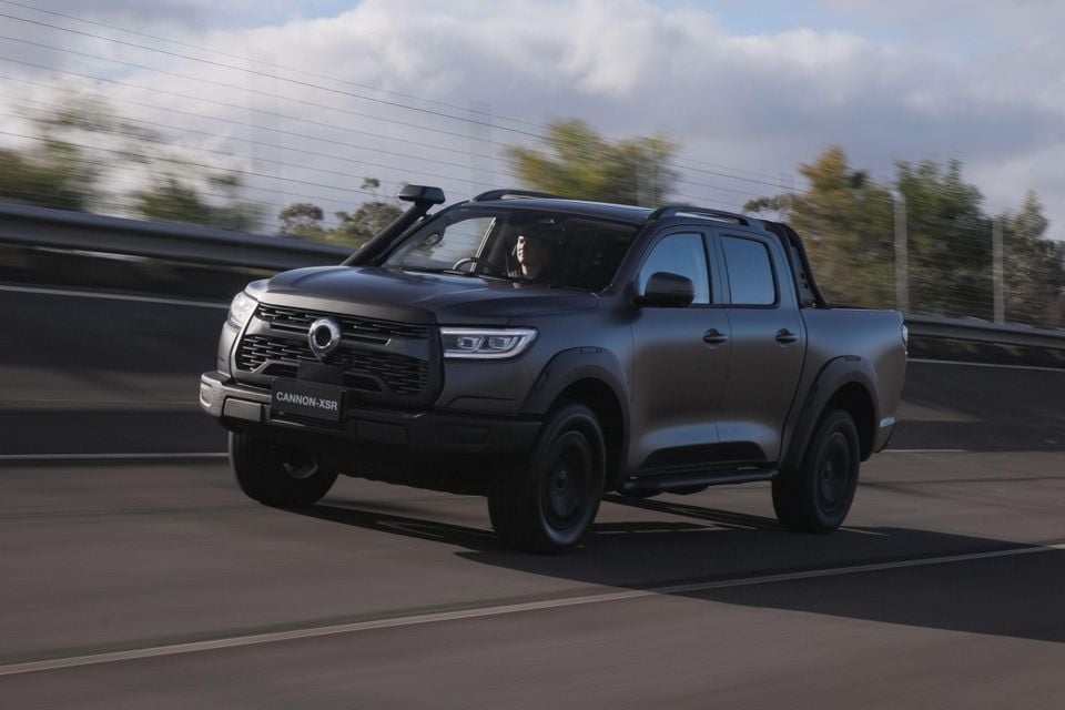 A dark grey GWM Cannon XSR dual-cab ute driving on a road, seen from the front-side