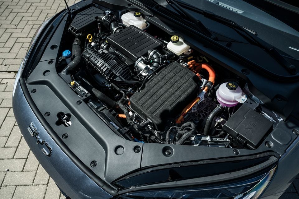Engine bay of a BYD Seal 6 hybrid, showing the combustion engine alongside orange high-voltage cables and electric drive components under an open bonnet