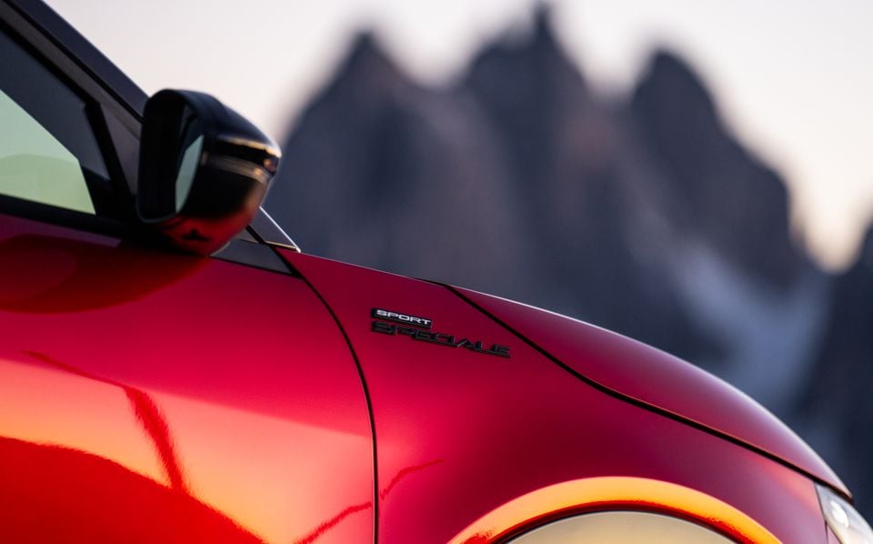 Close-up of the Sport Speciale badge on the front quarter panel of a red Alfa Romeo Junior Sport Speciale, with mountains in the background
