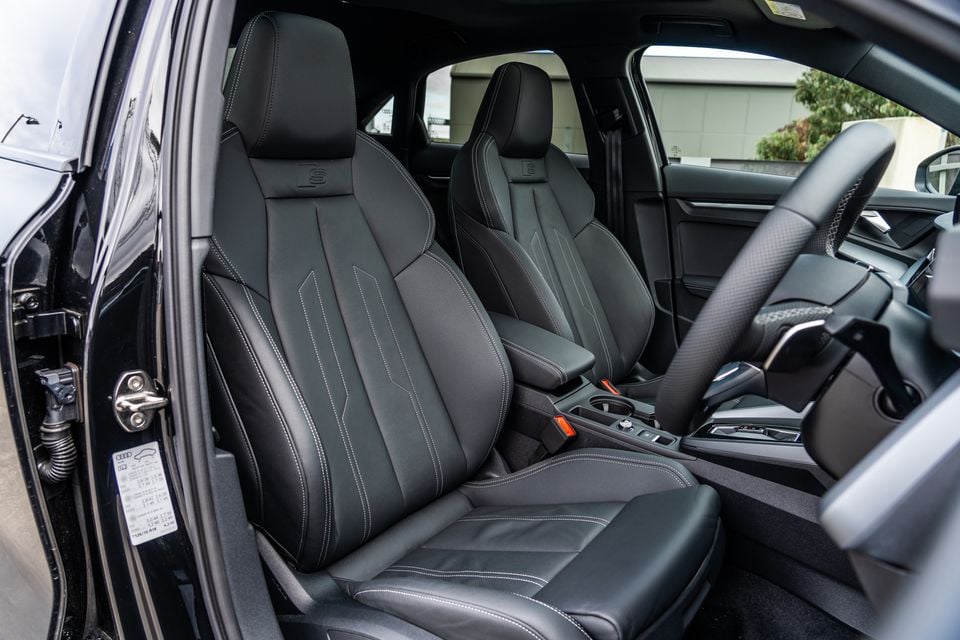 Black leather front seats with white contrast stitching inside a 2026 Audi A3 S line sedan, viewed from the open driver's door