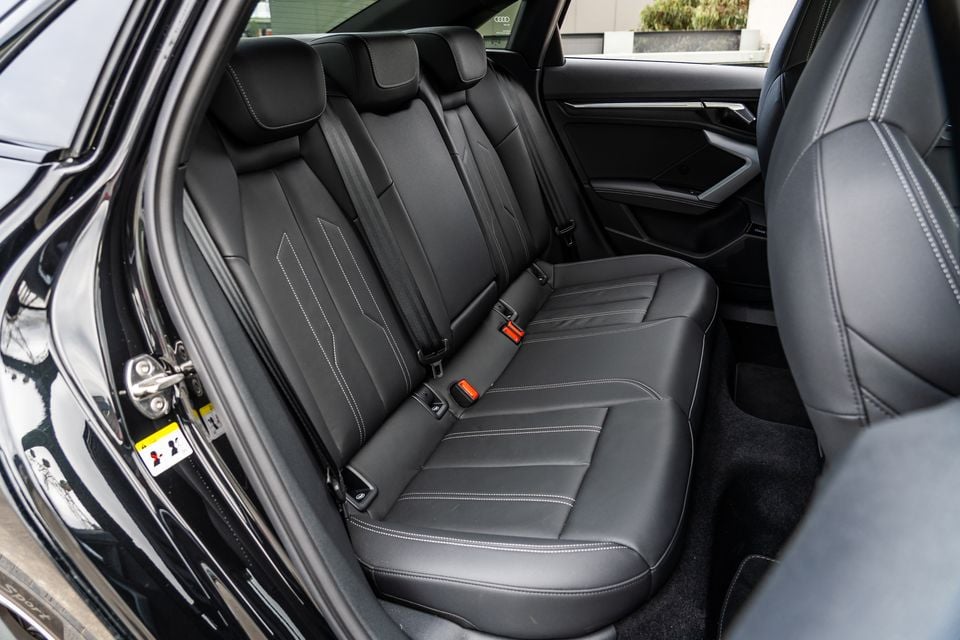 Rear passenger seats of a 2026 Audi A3 sedan, trimmed in black leather with white contrast stitching