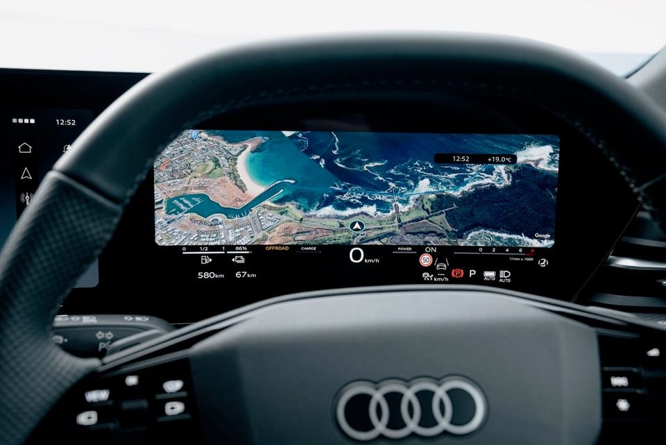 Audi Q5 digital instrument cluster displaying a Google satellite navigation map, with the Audi logo visible on the steering wheel
