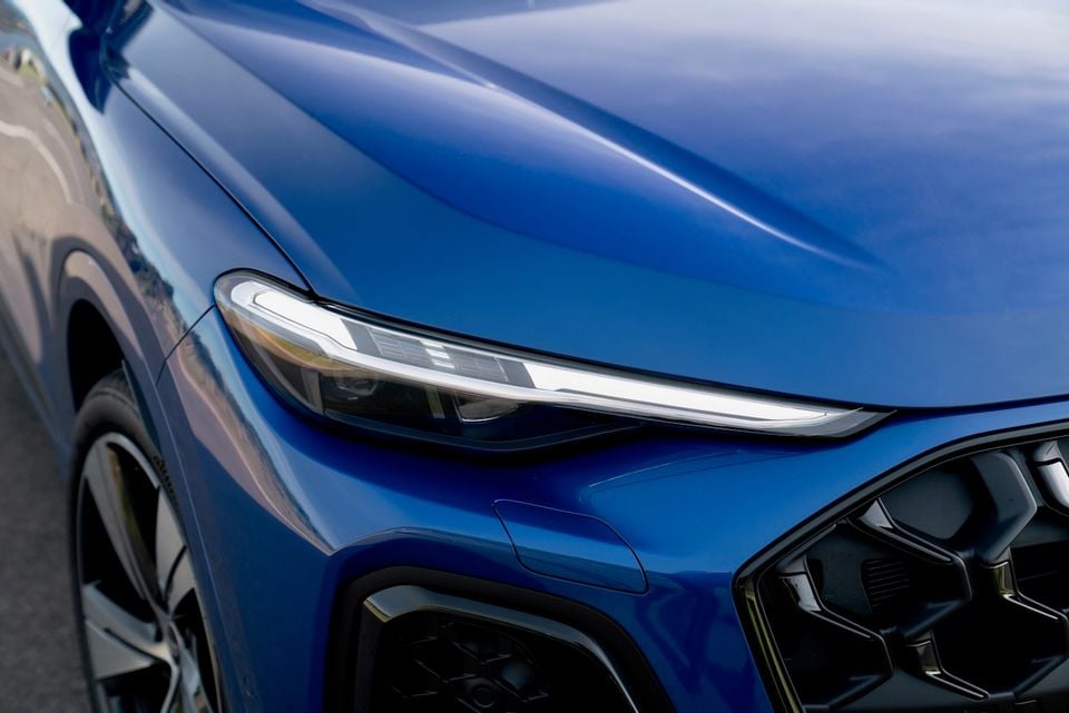 Close-up of the front headlight and bonnet of a blue 2026 Audi Q5 e hybrid SUV, showing the slim LED headlight and front grille detail.