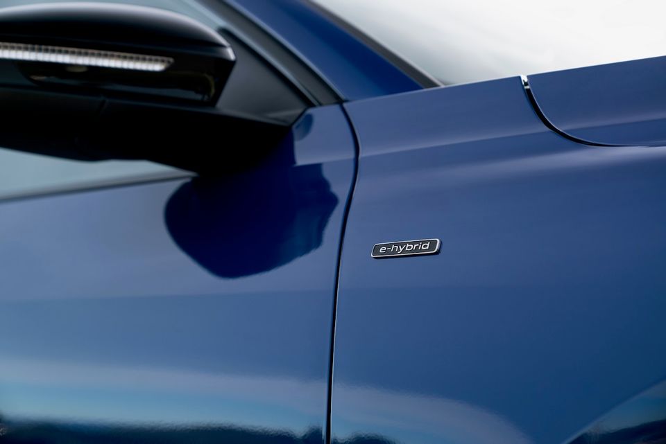 Close-up of the blue bodywork on a 2026 Audi Q5 e-hybrid, showing the 'e-hybrid' badge on the front door panel.