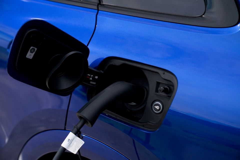 A charging cable plugged into the dual charging port of a blue Audi Q5 plug-in hybrid SUV