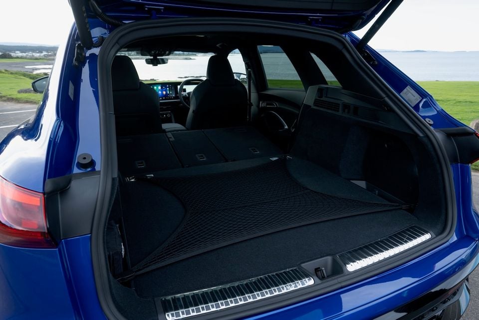Boot of a blue 2026 Audi Q5 SUV shown open with rear seats folded flat, revealing a large cargo area with a cargo net, viewed from the rear