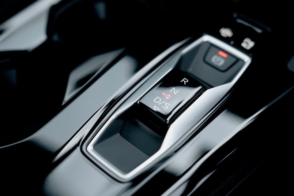 Close-up of the gear selector in a 2026 Audi Q5 e hybrid, showing R, N, D/S positions with a red indicator light and electronic park button nearby
