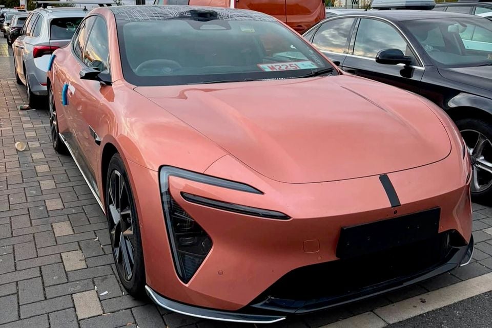 A pink/salmon 2026 Avatr 06T sedan seen from the front-side angle, parked in a car park