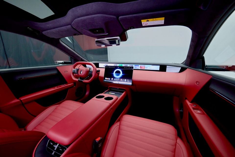 Interior of the 2026 Avatr 06T showing red leather seats, a yoke-style steering wheel, large central touchscreen, and wide panoramic display across the dashboard