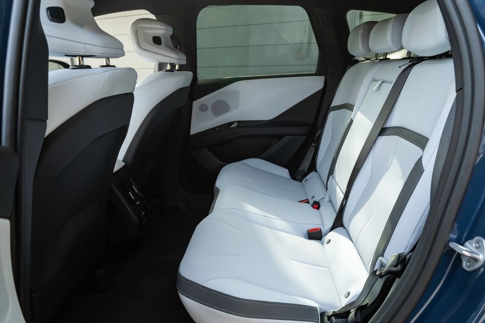 Rear seats of a 2026 BMW iX3 with light grey upholstery and contrasting grey accents, viewed through the open rear door