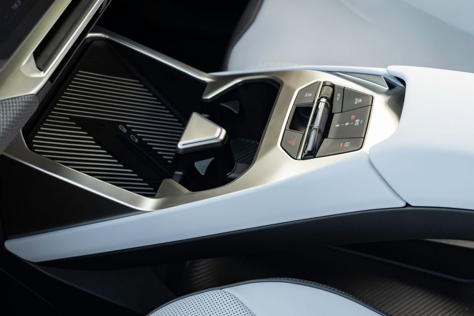 Close-up of the centre console in a 2026 BMW iX3, showing the gear selector, drive mode controls, and wireless charging pad with white leather trim