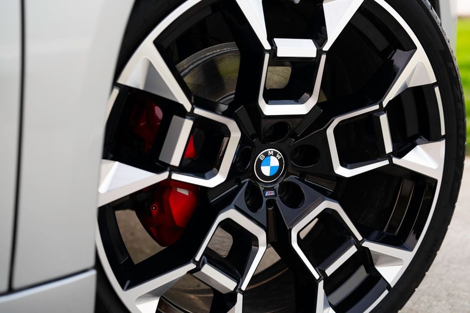 Close-up of a BMW M Sport alloy wheel with red brake caliper on a white 2026 BMW iX3 xDrive50 M Sport Pro