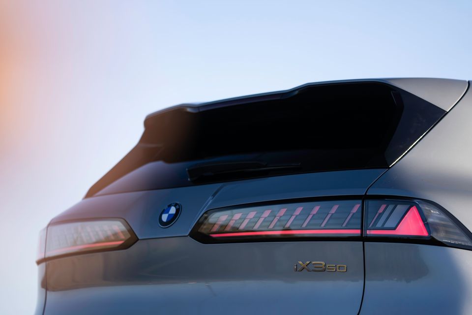 Close-up of the rear of a BMW iX3 50 showing the tail lights, BMW roundel badge, and iX350 model badge