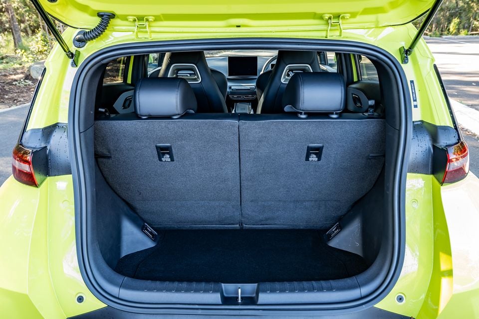 Open boot of a lime green 2026 BYD Atto 1 hatchback, showing a spacious carpeted cargo area with rear seats visible and the tailgate raised
