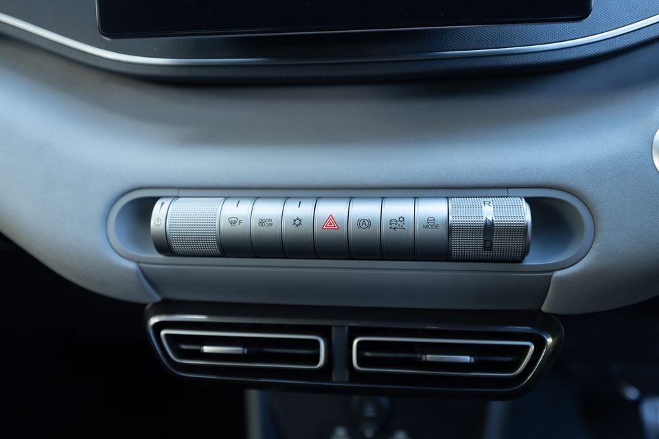 Close-up of the centre console control panel in a 2026 BYD Atto 1, showing a row of buttons including hazard lights, drive mode selector, and gear selector (R, N, D) with air vents below