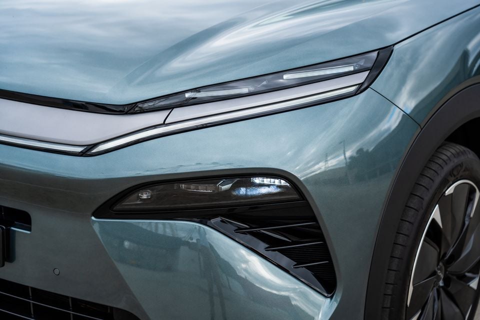 Close-up of the front corner of a light blue BYD Sealion 8, showing the LED headlight, fog light, and front bumper detail
