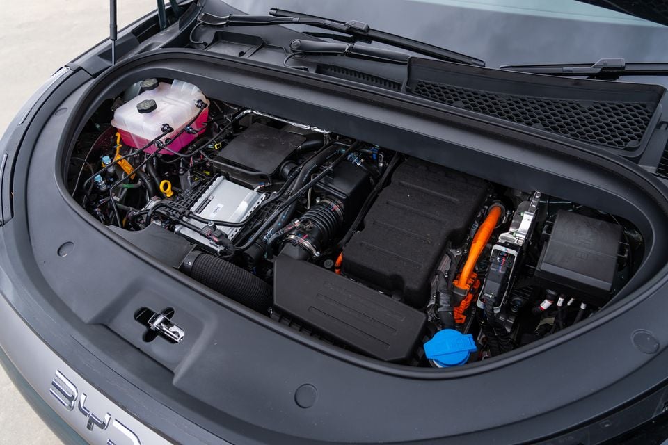 The engine bay of a BYD Sealion 8, showing the hybrid powertrain with orange high-voltage cabling and coolant reservoir visible under the open bonnet.