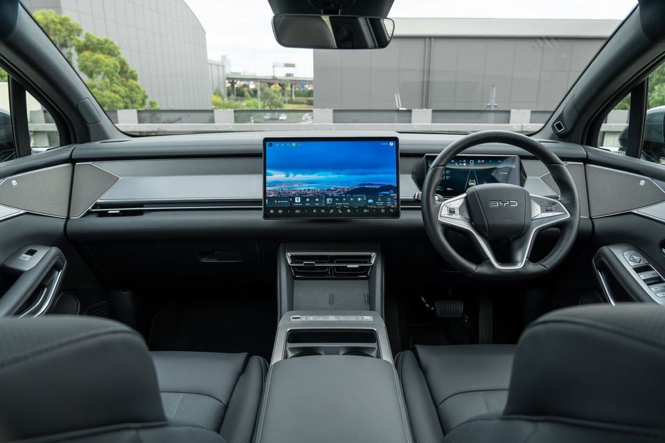 Interior of a BYD Sealion 8 showing the dashboard, large central touchscreen infotainment display, digital instrument cluster, and steering wheel with BYD logo, in right-hand drive configuration
