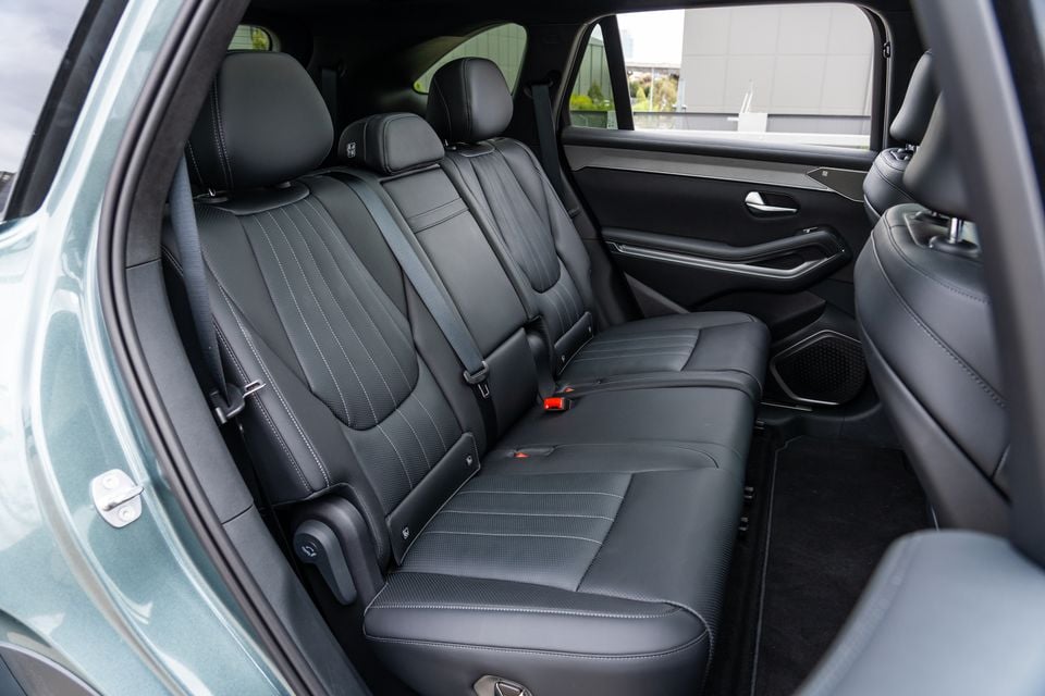 Rear seat interior of a BYD Sealion 8 SUV showing black leather and fabric upholstery with white stitching, seatbelts, and a door-mounted speaker
