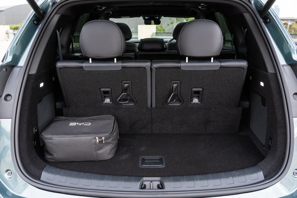 Boot space of a BYD Sealion 8 SUV, showing a carpeted cargo area with top tether anchor points on the rear seat backs and a BYD branded bag sitting in the boot.