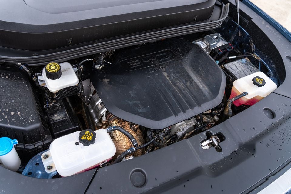 Engine bay of the 2026 BYD Shark 6 plug-in hybrid ute, showing the BYD-branded engine cover, coolant reservoirs and brake fluid reservoir