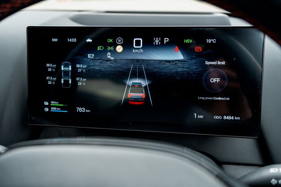 Digital instrument cluster in the 2026 BYD Shark 6 showing tyre pressures, hybrid range, speed and a ute driving graphic, seen through the steering wheel