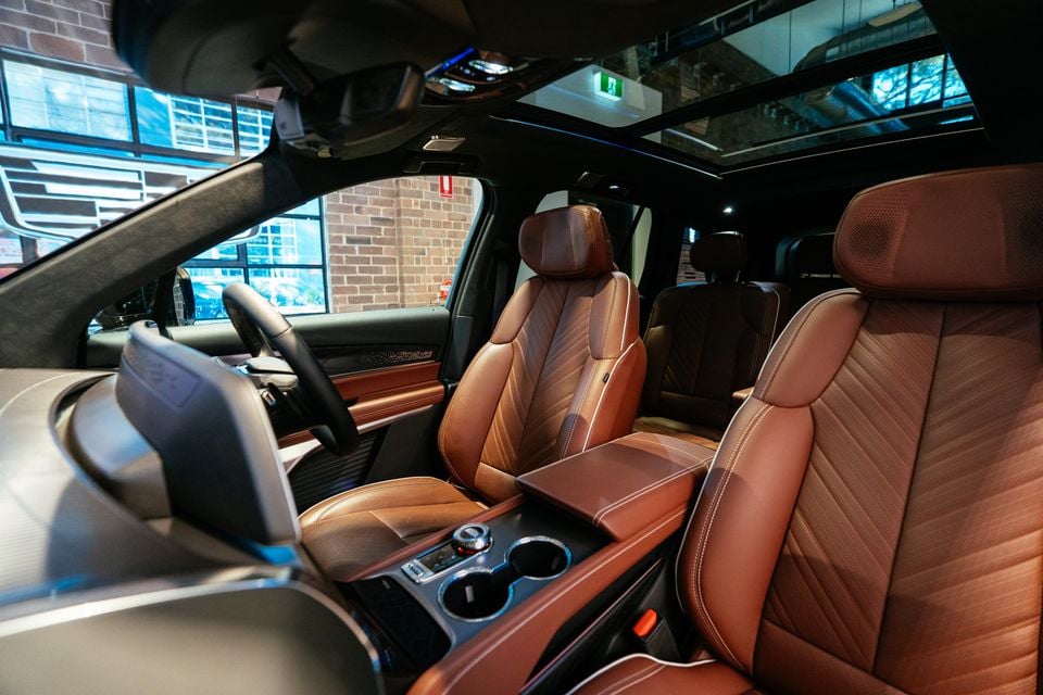 Interior of the 2026 Cadillac VISTIQ Platinum showing tan leather seats with contrast stitching, centre console, and panoramic sunroof