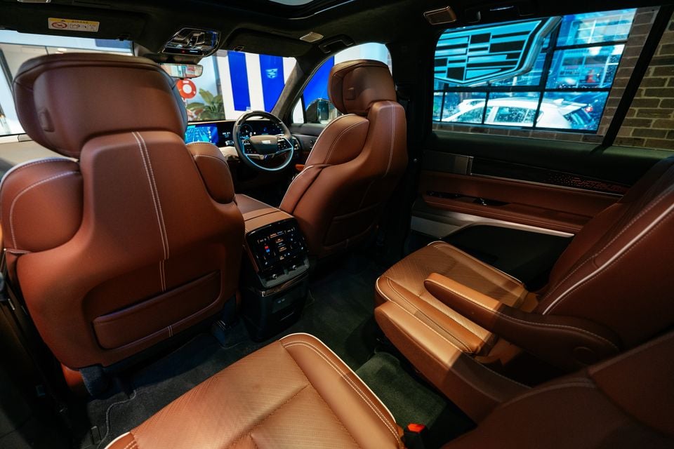Interior of the 2026 Cadillac VISTIQ Platinum showing tan leather captain's chairs, centre console with touchscreen controls, and the dashboard with digital displays visible in the background