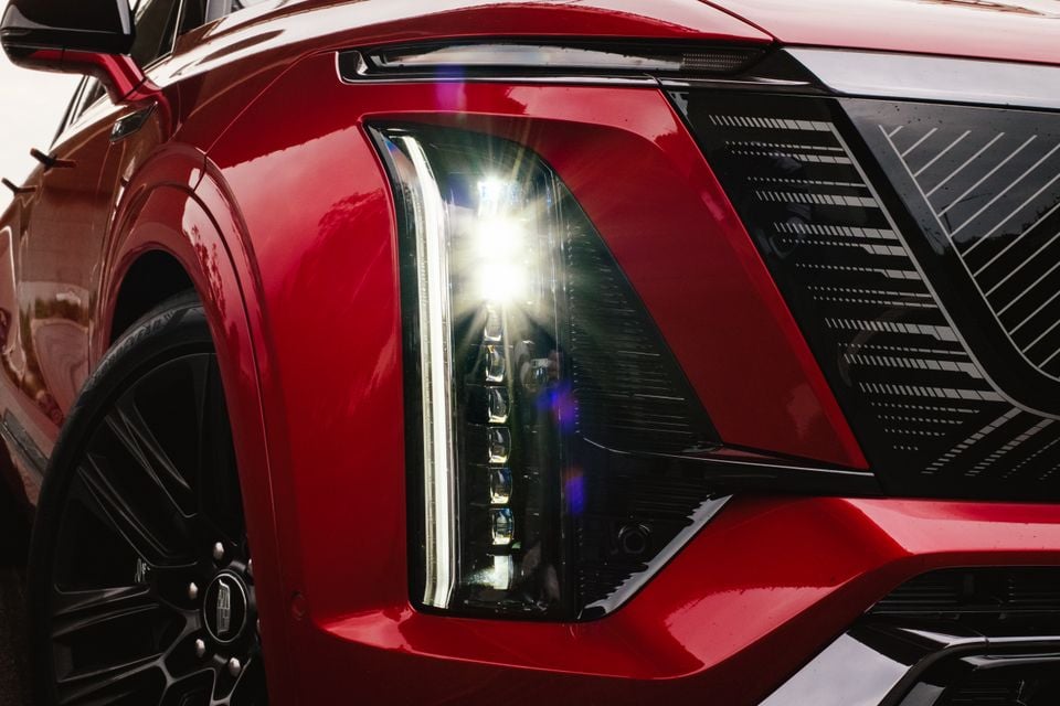 Close-up of the LED headlight and front grille on a red Cadillac Vistiq SUV